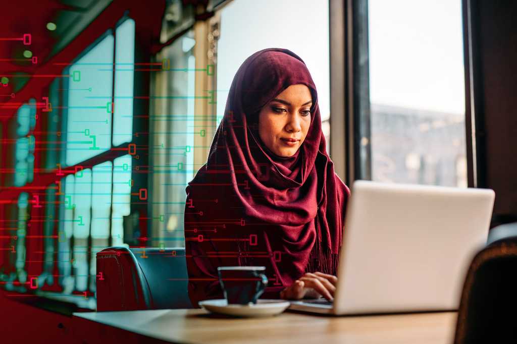 CIO | Middle East  >  A woman uses a laptop amidst abstract binary data.